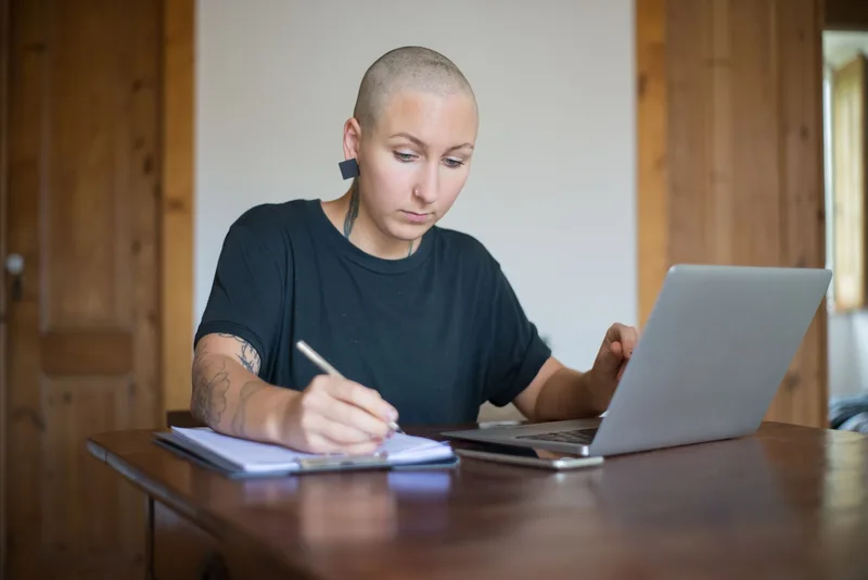 Solo creator filming a casual “day in my life” Story on their phone at a home office desk, showing the real behind-the-scenes of content creation